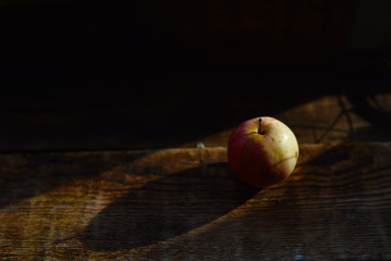 a small ripe Apple on a wooden table in the sunlight