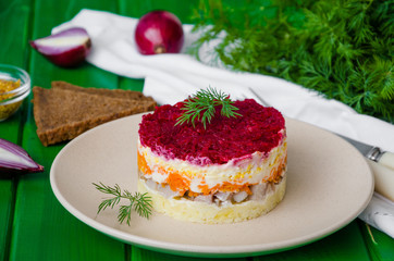 Traditional festive Russian salad herring under a fur coat on the plate. Salad with salty fish and boiled vegetables. 