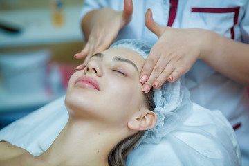 Fototapeta na wymiar people, beauty, lifestyle and relaxation concept - beautiful young woman lying with closed eyes and having face and head massage at spa