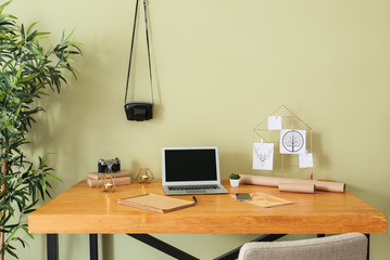Comfortable workplace with laptop and moodboard in room