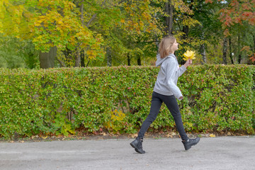 Fototapeta premium Young beautiful woman is playing with autumn leaves in the park