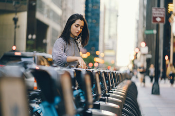 girl renting a city bike from a bike stand in chicago