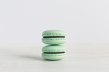 Two French macarons on a white wooden table. Mint macarons. White background.