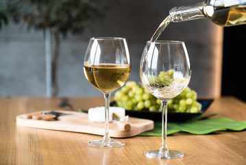 Waiter pouring white wine into wineglass. 