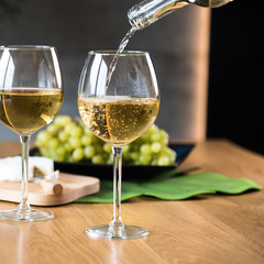 Waiter pouring white wine into wineglass. 