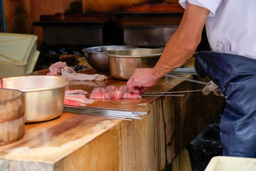Japanese chef cook Unagi or eel being grilled , many pot and kitchenware on wooden table, chef prepared skewered raw fresh stick eel seafood (Unagi) before girll in  restaurant ,Japan