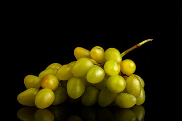 A bunch of grapes on a table of glass on a black background