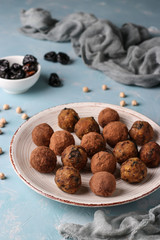 Energy balls of chickpea, prunes and dates, sprinkled with cocoa on a plate on a light blue background, vertical orientation, top view
