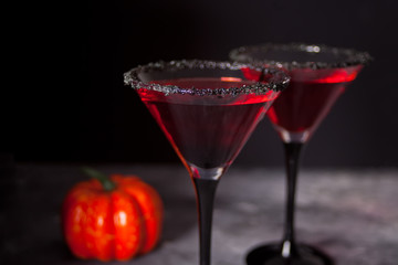 Two glasses with red cocktail, dried roses for Halloween party on the dark background