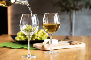 Waiter pouring white wine into wineglass. 