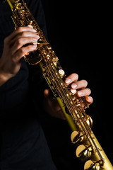 soprano saxophone in hands on a black background