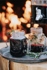 Decorated Christmas table with a glass of mulled wine on the background of a burning fireplace