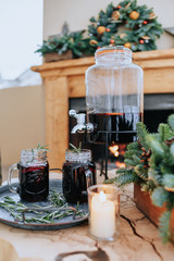 Decorated Christmas table with a glass of mulled wine on the background of a burning fireplace