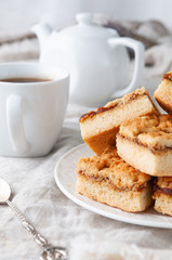 Homemade shortbread cookies stuffed with apple jam. In a white plate. On a linen tablecloth of gray color. In the background is a teapot and cup.