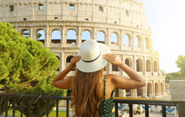 Travel in Italy. Back view of beautiful girl visiting Colosseum landmark at sunset in Rome. Summer holidays in Europe. - obrazy, fototapety, plakaty
