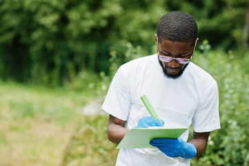 African volunteer man with clipboard in park. Africa volunteering, charity, people and ecology concept.