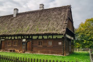 Fototapeta na wymiar stara drewniana chałupa wiejska kryta słomianą strzechą, małe okna wiejskiego domu,