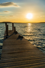 Fototapeta na wymiar Orange summer sunset at a lake behind a jetty