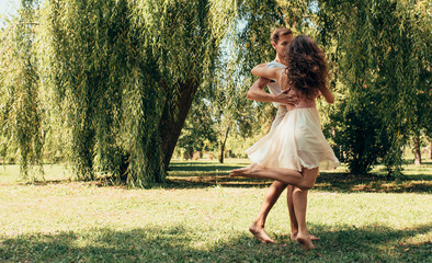 Horizontal outdoor image of romantic couple in love dating outdoors at the park on a sunny day. Happy couple in love dancing together. Date day. Valentine day