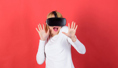 Fototapeta na wymiar Woman watching virtual reality vision. Amazed young woman touching the air during the VR experience. Portrait of an amazed girl using a virtual reality headset isolated on red background.