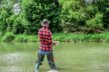 hobby and sport activity. pothunter. fisherman with fishing rod. mature man fly fishing. man catching fish. bearded fisher in water. summer weekend. Big game fishing. Gotta Hook Them To cook Them.