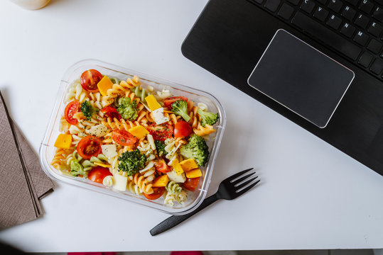 Healthy food in lunch box, on working table with laptop