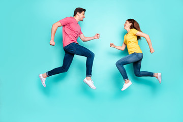 Fototapeta na wymiar Full length body size profile side view of nice attractive sportive active cheerful cheery couple running jumping in air having fun isolated over bright vivid shine vibrant green turquoise background