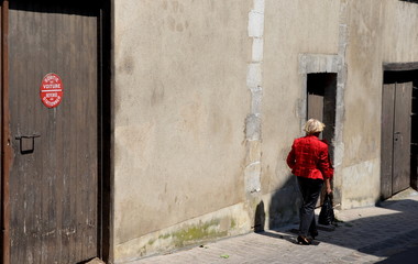Une femme habillée de rouge marchant dans une rue de ville. Une femme de dos marchant dans une rue.