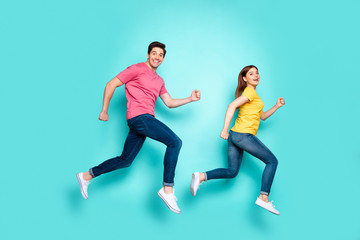 Fototapeta na wymiar Full length body size profile side view of nice attractive funny cheerful cheery couple running fast speed in air having fun isolated over bright vivid shine vibrant green turquoise background
