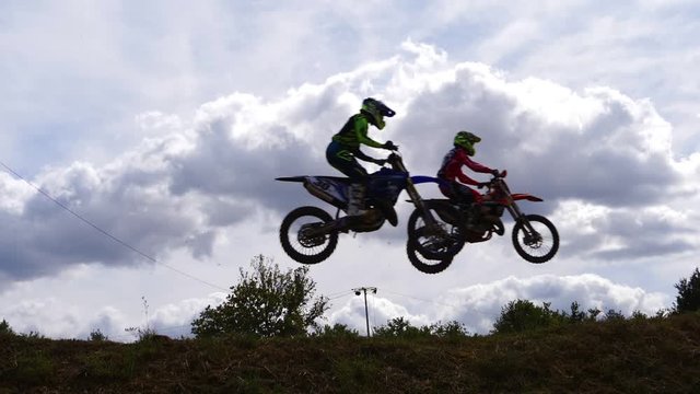Silhouette shot of motocross racer jumping against sky. Slow motion.