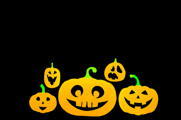 A colored background from a group of pumpkins cut out of orange paper isolated on a black background with a place for notes, ideal for the holiday of all saints - Halloween.