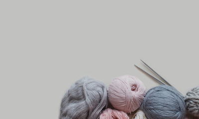 Woolen yarn and knitting needles on grey backdrop