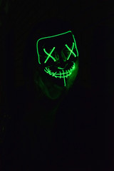 Portrait of female model in scary Halloween mask in the darkness