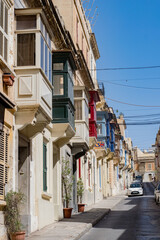 Fototapeta na wymiar Perspective view of residential buildings colorful balconies in Valetta, Malta. Narrow mediterranean city street. Travel destination concept.