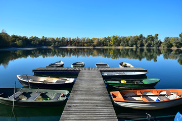 Autumn landscape with a lake, a boat bridge and some boats.