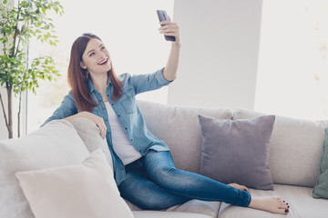Photo of amazing lady telephone in hands making selfies for social network blog sitting comfy sofa wearing jeans clothes apartment indoors