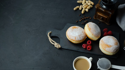 Pączki z cukrem pudrem. Maliny, orzechy, kawa. Ciemne tło, widok z góry. © PhotoHunter