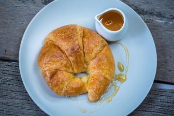 Croissants topped with honey on a white plate