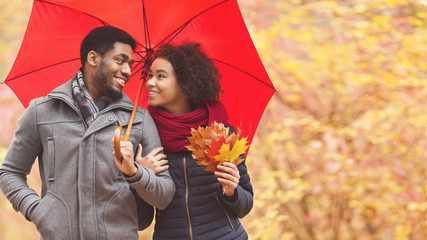 Family walk. Afro couple under umbrella at rainy day
