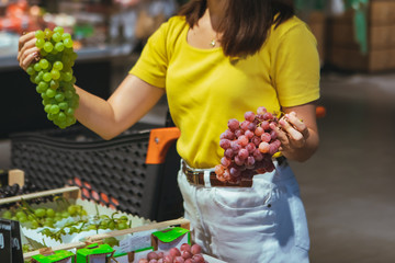 woman buying grapes in store