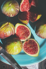 Whole and half cut ripe figs on blue plate; fruit background