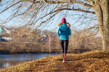 Back view of running girl in fall park in morning