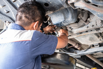 Thai mechanic fix car at the garage and change engine oil. He standing under the car on lift...