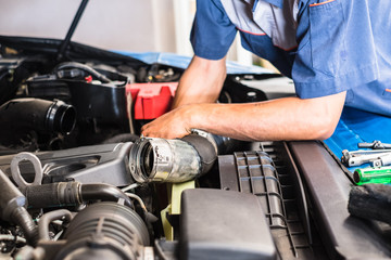 Obraz premium Zbliżenie ramienia mechanika umieszczającego na otwartej przedniej masce silnika samochodu. Mechanik samochodowy sprawdzający silnik samochodu.