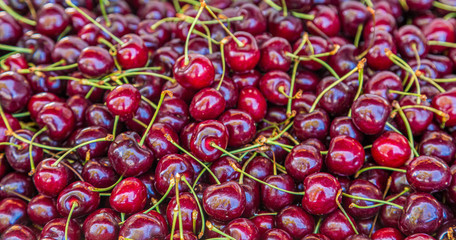 A bin full of fresh cherries with stems. Good for marketing or backgrounds