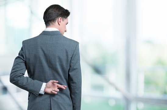 Businessman with his fingers crossed behind his back - concept for good luck or dishones