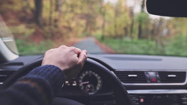 Point of View: Man Hands Driving a Car, Looking for Directions in a Paper Map. SLOW MOTION CLOSE UP. Unrecognizable male driver hands holding steering wheel, POV.