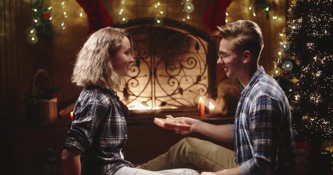 Cute caucasian couple exchanging their presents in a specially decorated room, spending holidays together - christmas spirit, holidays and celbrations concept 4k footage
