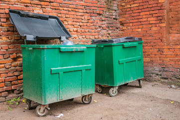 Garbage cans near an old brick wall on a city street