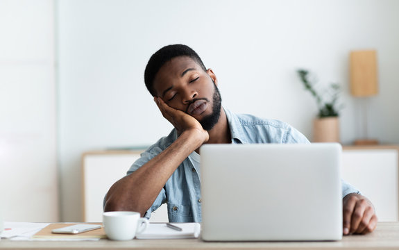 Exhausted African American worker felt asleep at workplace